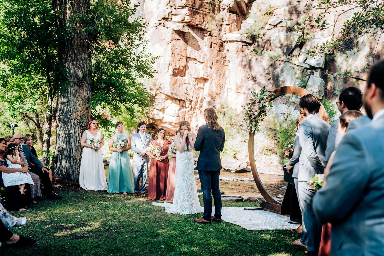 Wide view of an outdoor wedding ceremony against dramatic red rock cliffs.