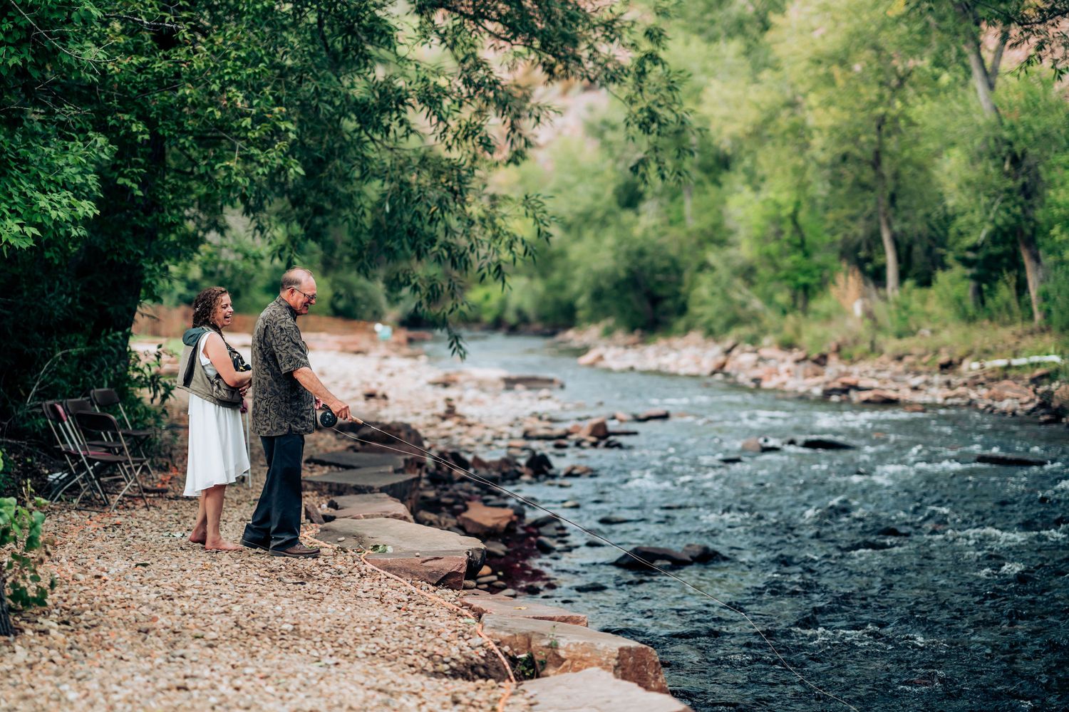 Couple standing by a rushing river surrounded by lush greenery on a nature trail.