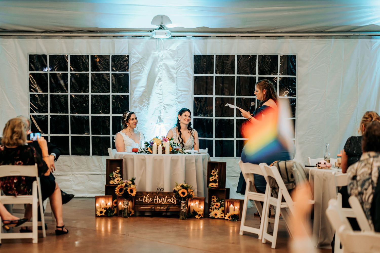 Wedding reception head table setup with decorative lighting and table settings.