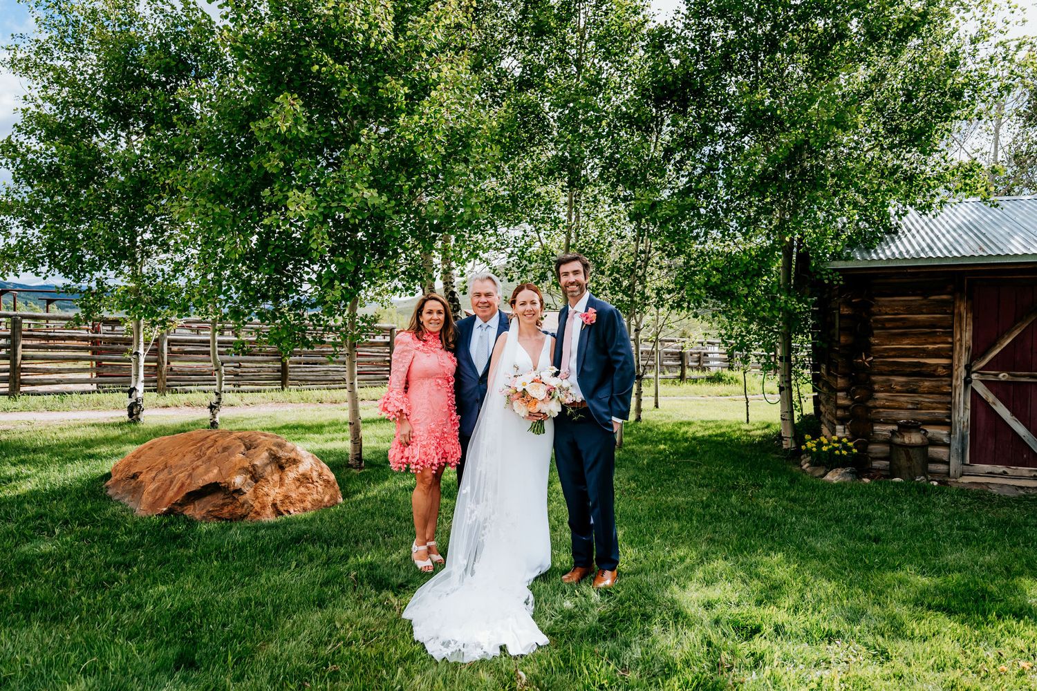 Wedding group poses outdoors with a resting brown cow in the background.