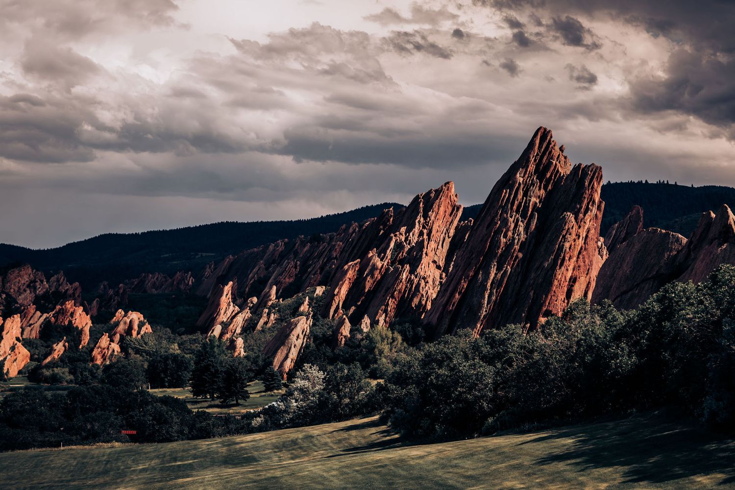 Dramatic red rock formations at Garden of the Gods in Colorado under stormy skies at sunset.
