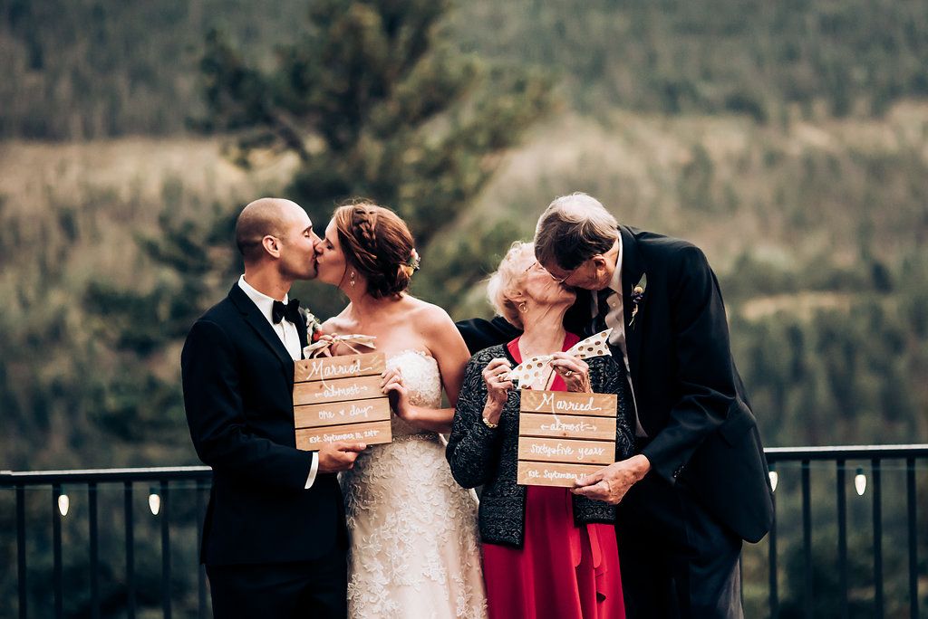 Two couples share intimate moments with wooden boxes on mountain overlook balcony.