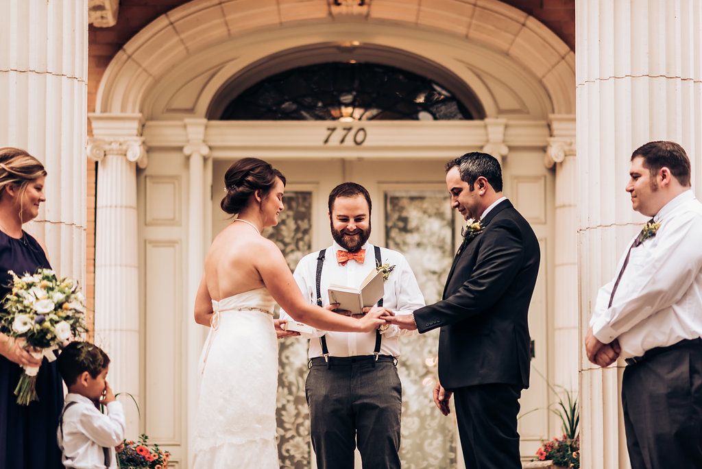 Wedding exchange of rings on grand steps with classical architectural details.