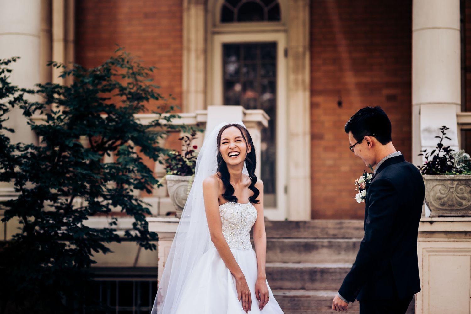 A charming wedding moment captured on the steps of a historic brick building.