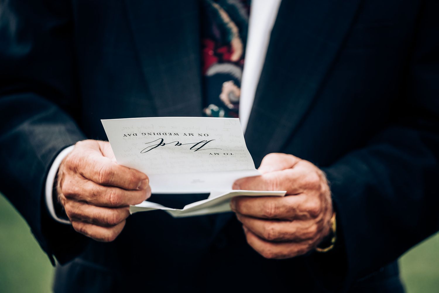 Hands holding a wedding invitation card with elegant script writing.