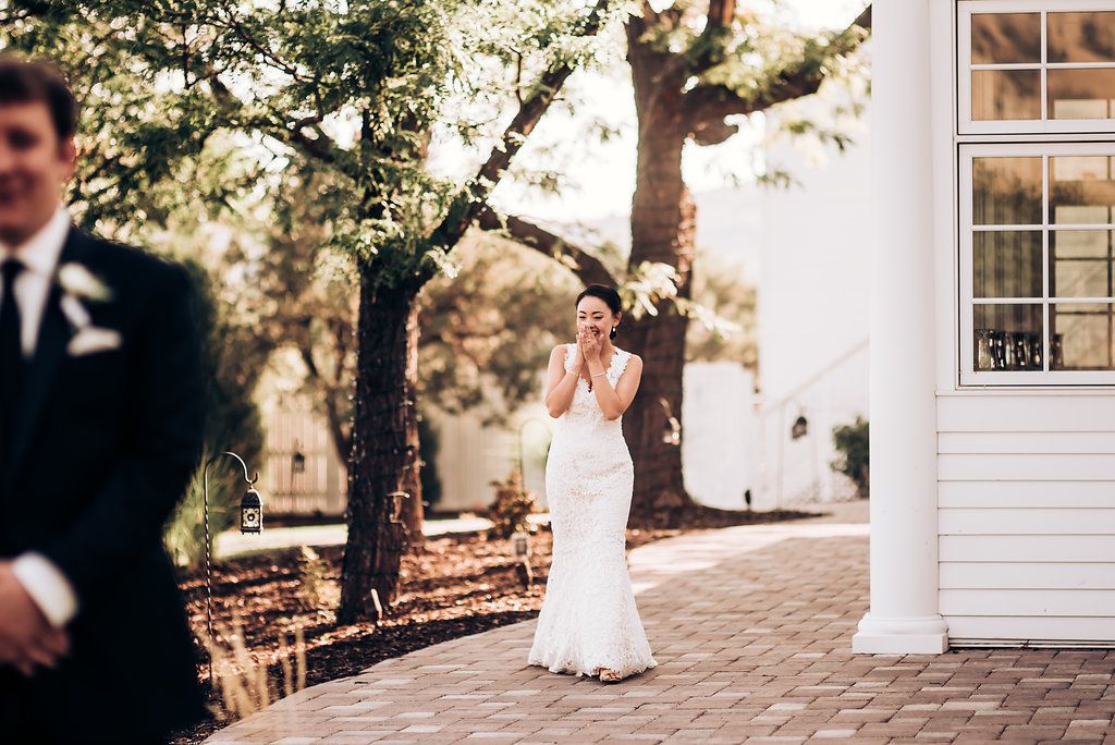 Elegant outdoor first look moment at a white colonial style wedding venue.