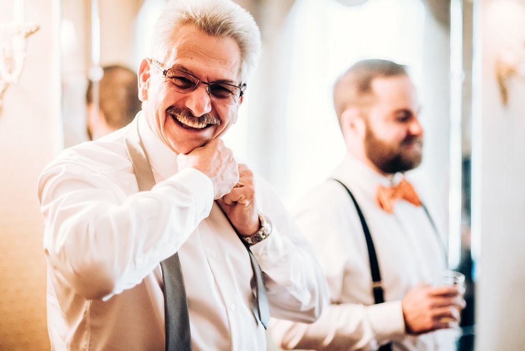 Two men in formal attire getting ready and adjusting their clothing before an event.