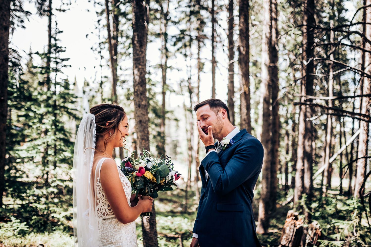 A tearful reaction during a wedding ceremony surrounded by tall pine trees in a forest.
