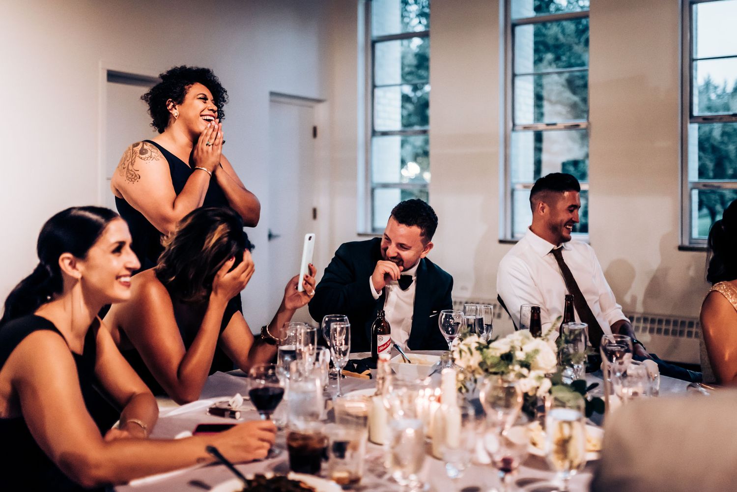 Candid reception moment captures laughter and joy among wedding guests at dinner table.
