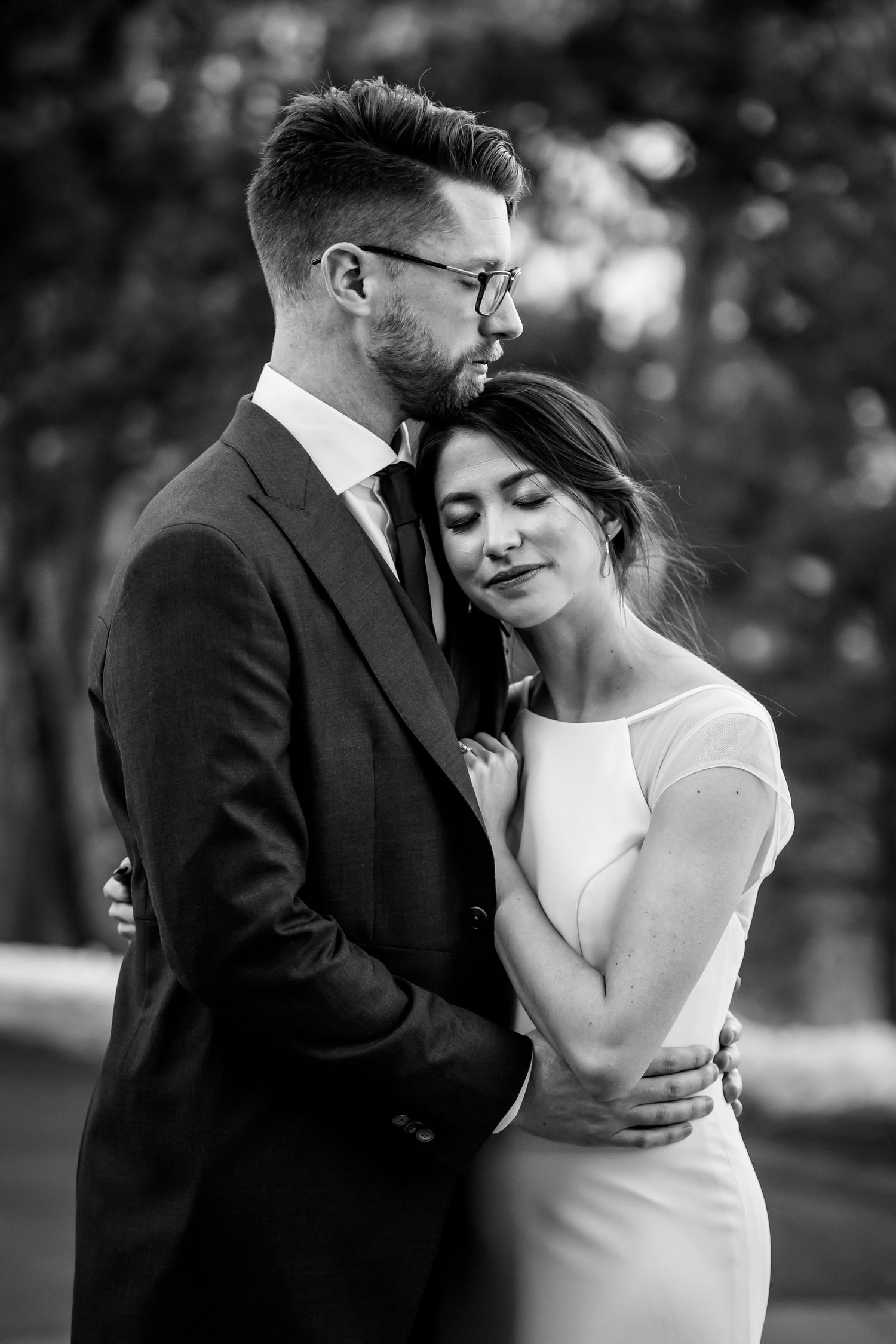 Intimate black and white portrait of a couple sharing a romantic moment outdoors.