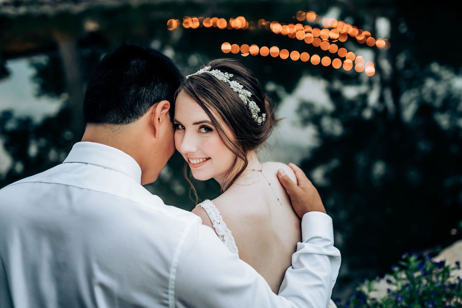 An intimate moment captured between newlyweds with bokeh lights creating a romantic evening atmosphere.