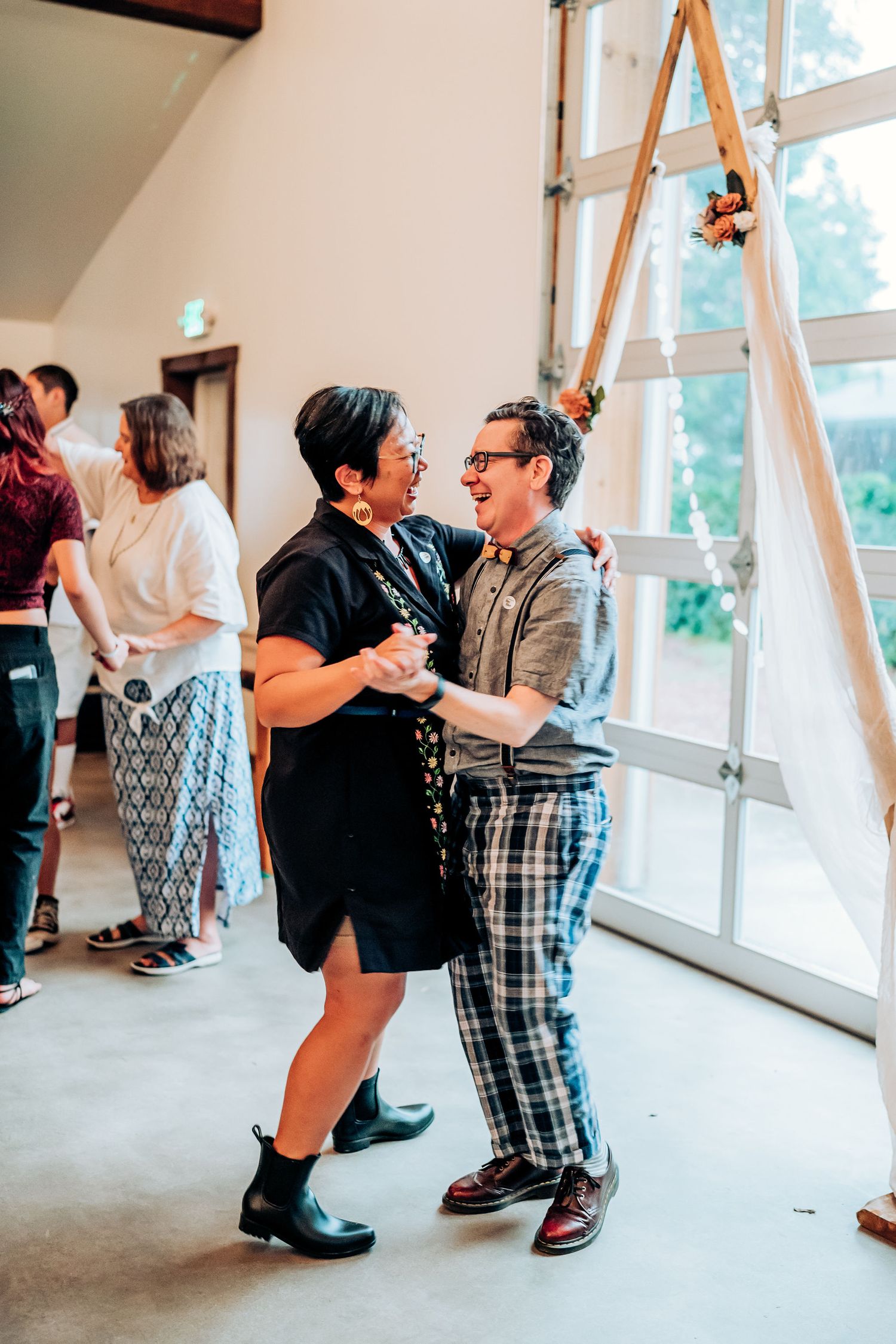 Dancing couple enjoying a lively moment at an indoor event with natural lighting.