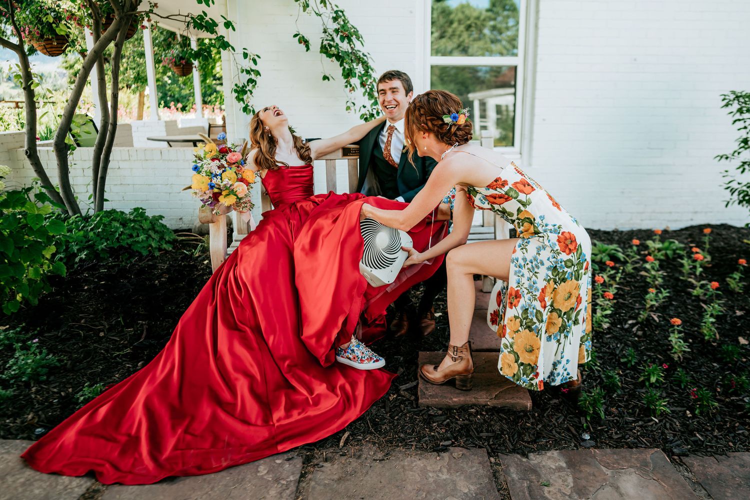 Fun wedding party photo with flowing red dress on white building steps.