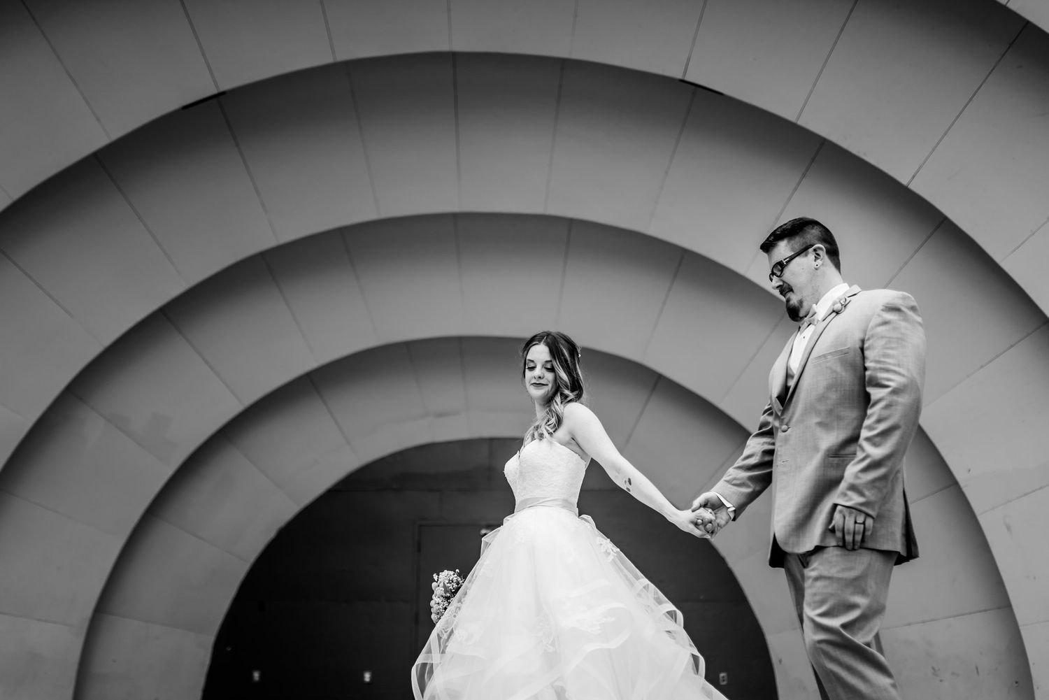 Black and white wedding portrait against geometric circular archway backdrop.