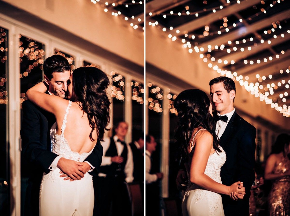 Couple dancing intimately at wedding reception under romantic string lights in elegant venue.