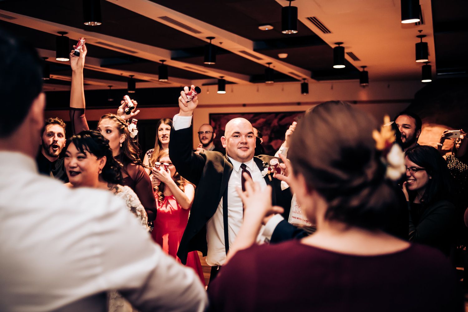 Wedding guests raising their arms in celebration during a reception party.
