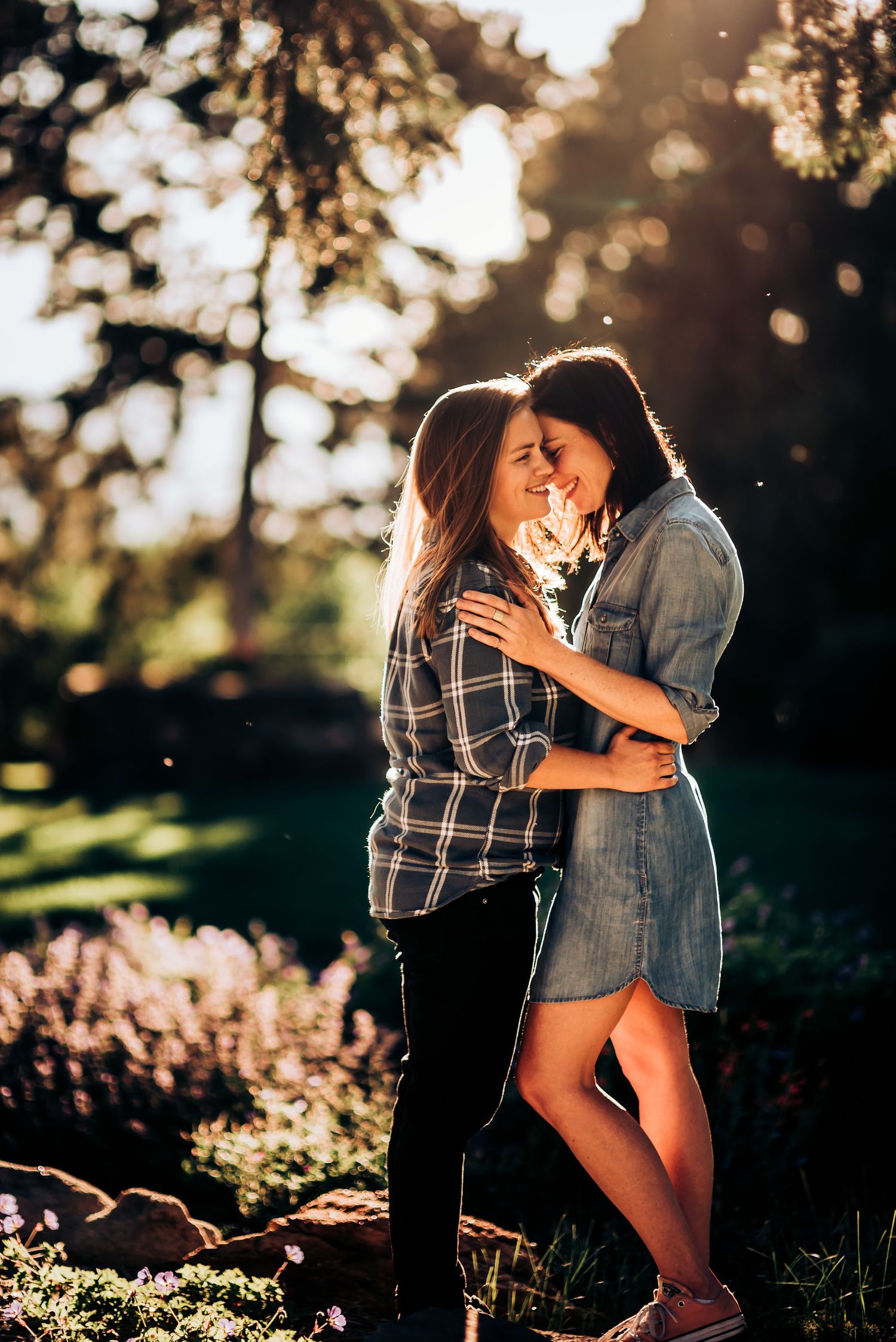 Couple sharing an intimate moment in golden sunset light among trees and grass.