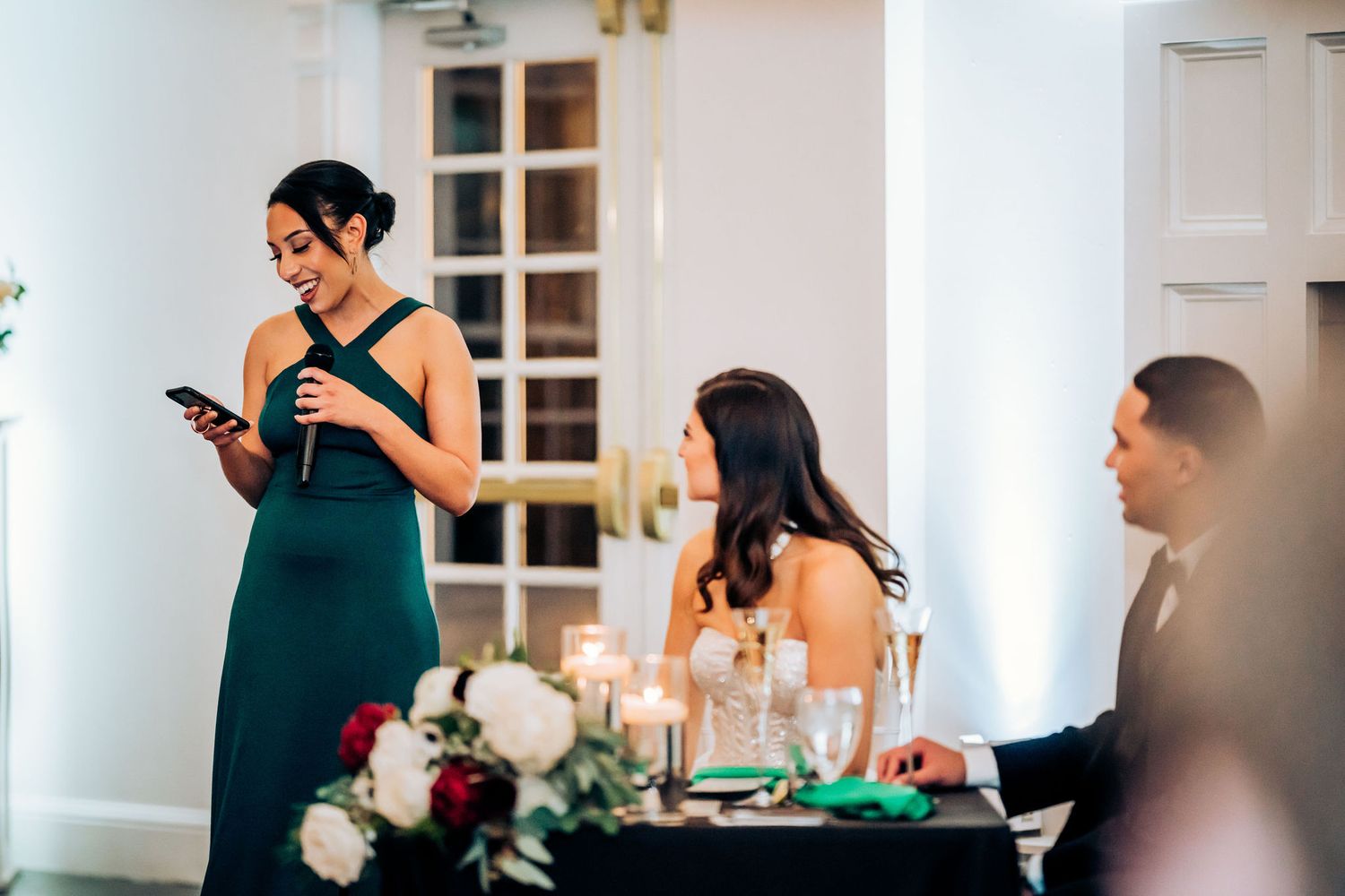 Guest giving a speech at an elegant wedding reception with formal table settings and floral decorations.