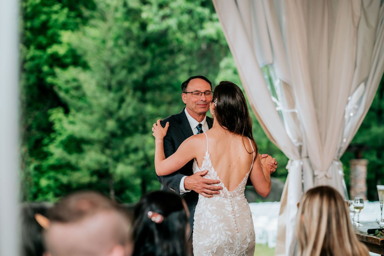 Dancing at a wedding reception under elegant white drapes and greenery.