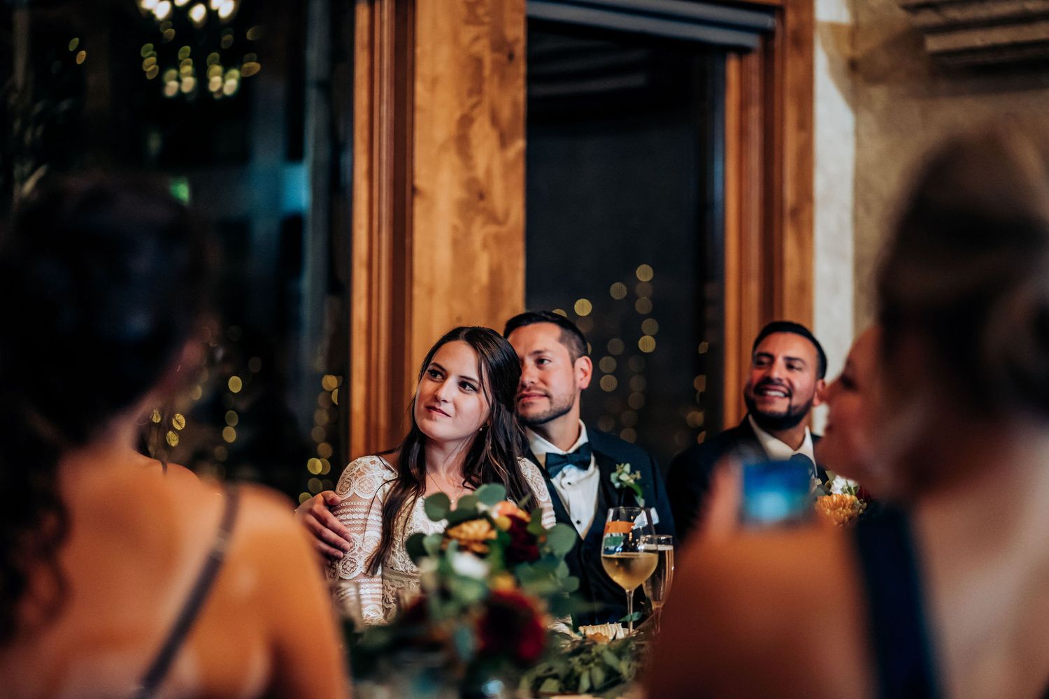Wedding reception guests enjoy dinner conversations in an elegantly lit venue.
