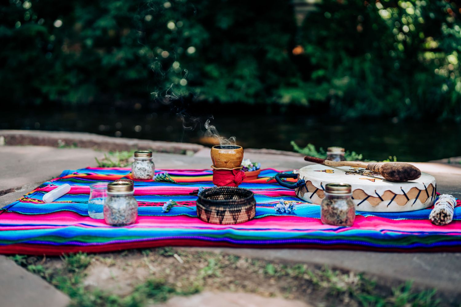 Colorful ceremonial objects and vessels arranged on a striped textile.
