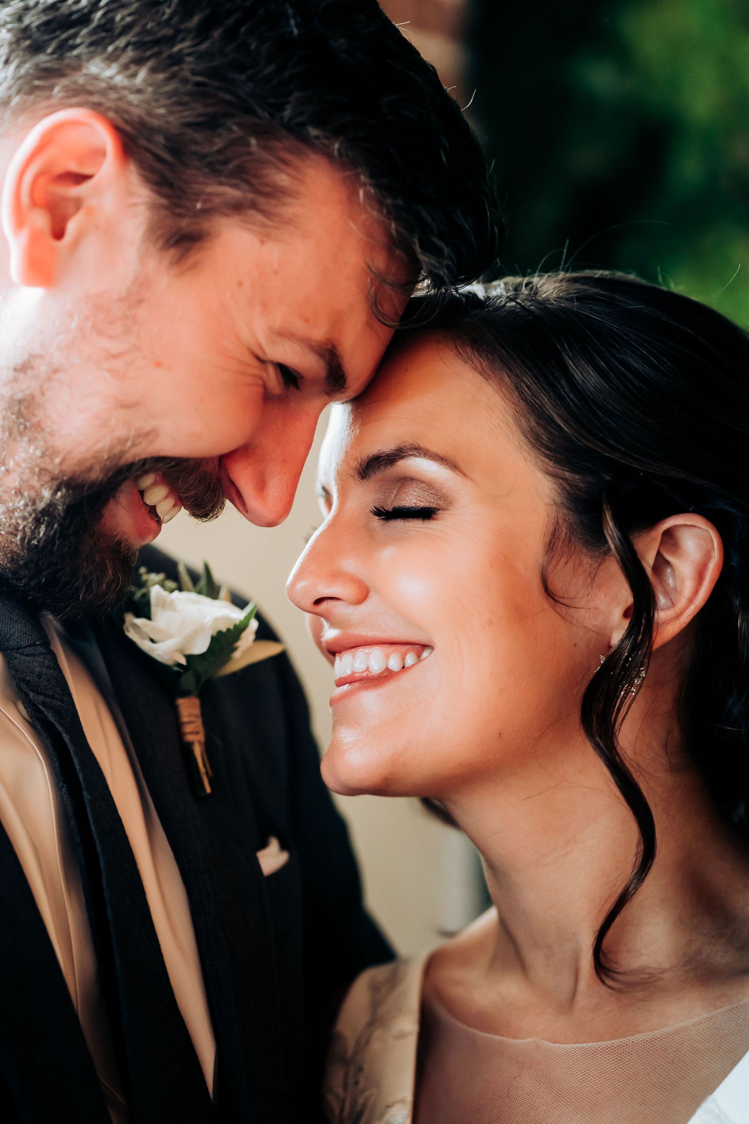 Romantic close-up of newlyweds touching foreheads and smiling with pure joy.