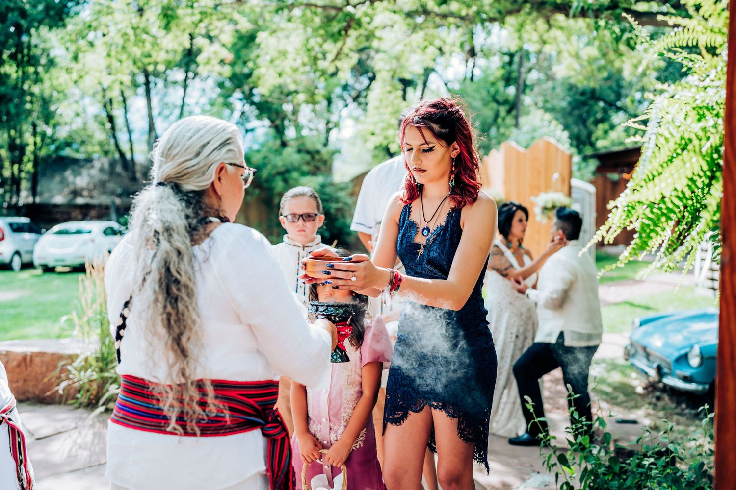 Guests mingling at an outdoor garden party with natural greenery backdrop.