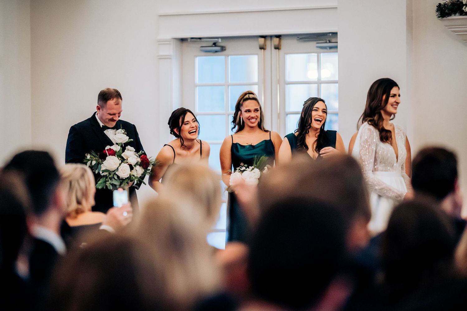 A joyful group watches from the front row during an elegant indoor wedding ceremony.