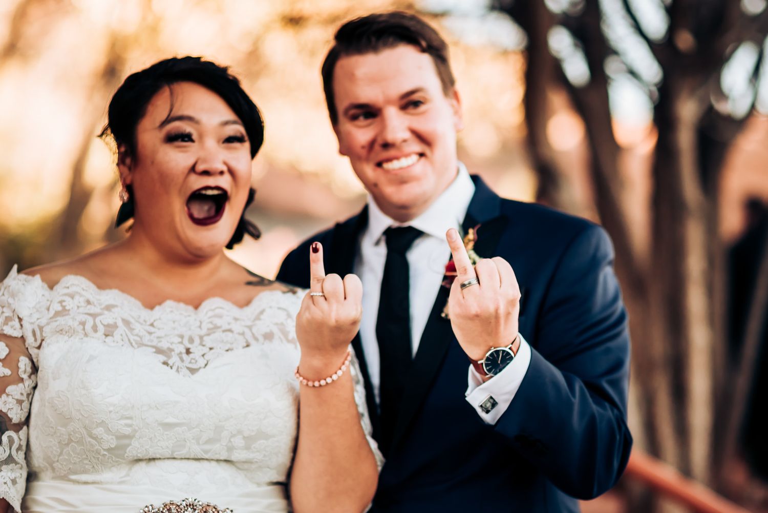 Candid celebratory moment at outdoor wedding with white lace dress and navy suit.