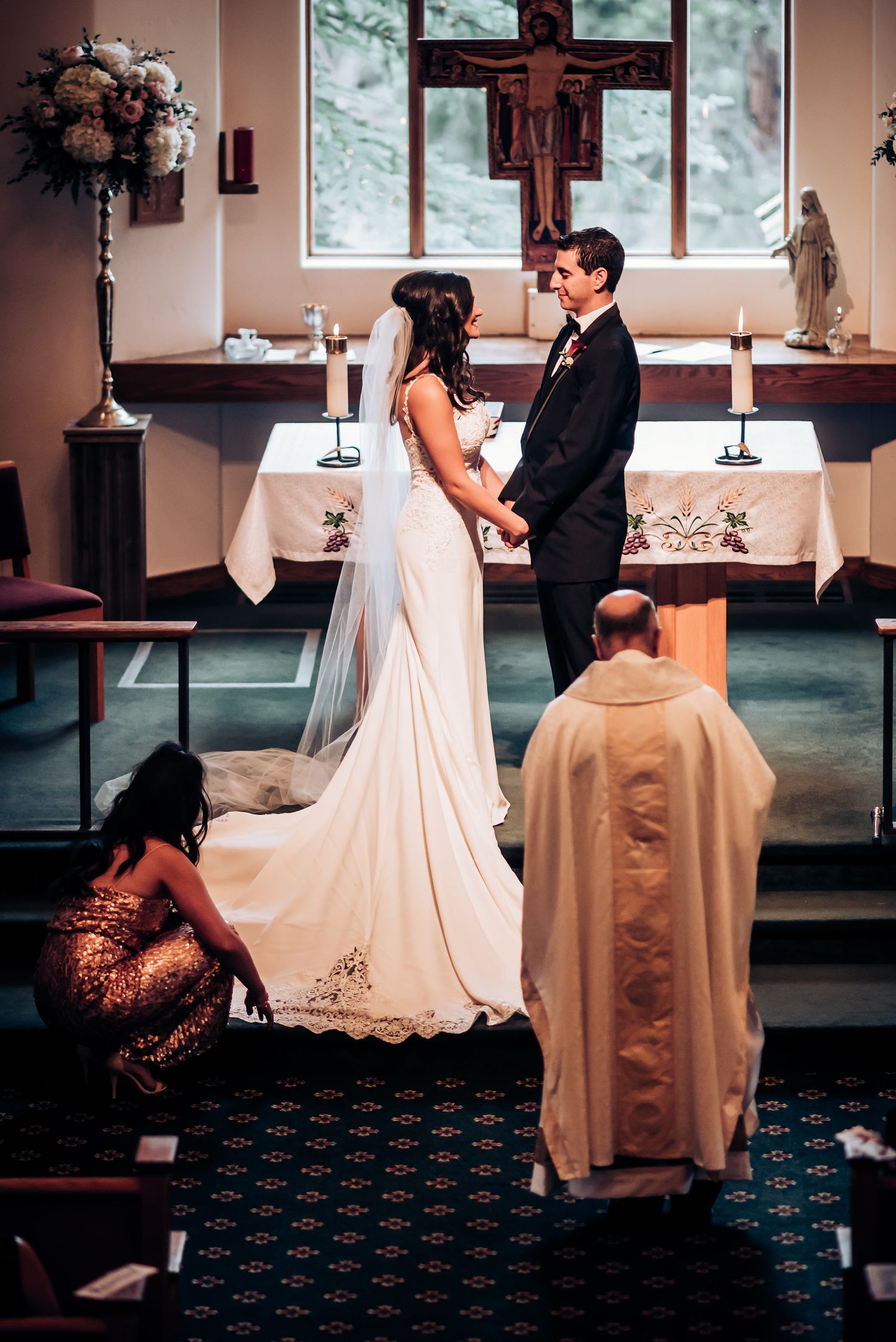 A wedding ceremony in progress with priest presiding at ornate church altar.