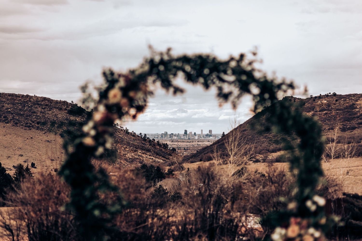 Floral arch overlooking a scenic mountain landscape with natural foliage and distant hills.