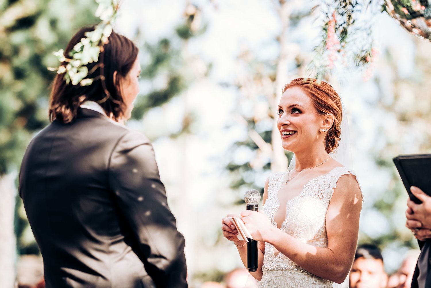 A joyful outdoor wedding ceremony with a couple exchanging vows under natural lighting.