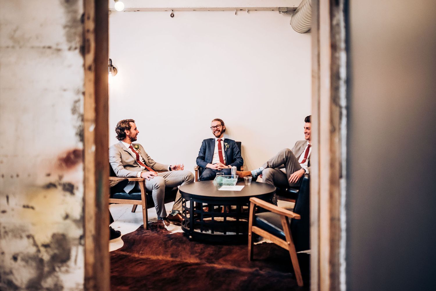 Group gathered around table in rustic room having conversation.