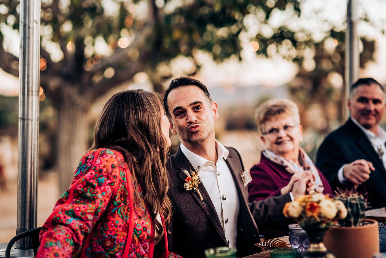 Intimate outdoor celebration with guests seated at decorated dining table.