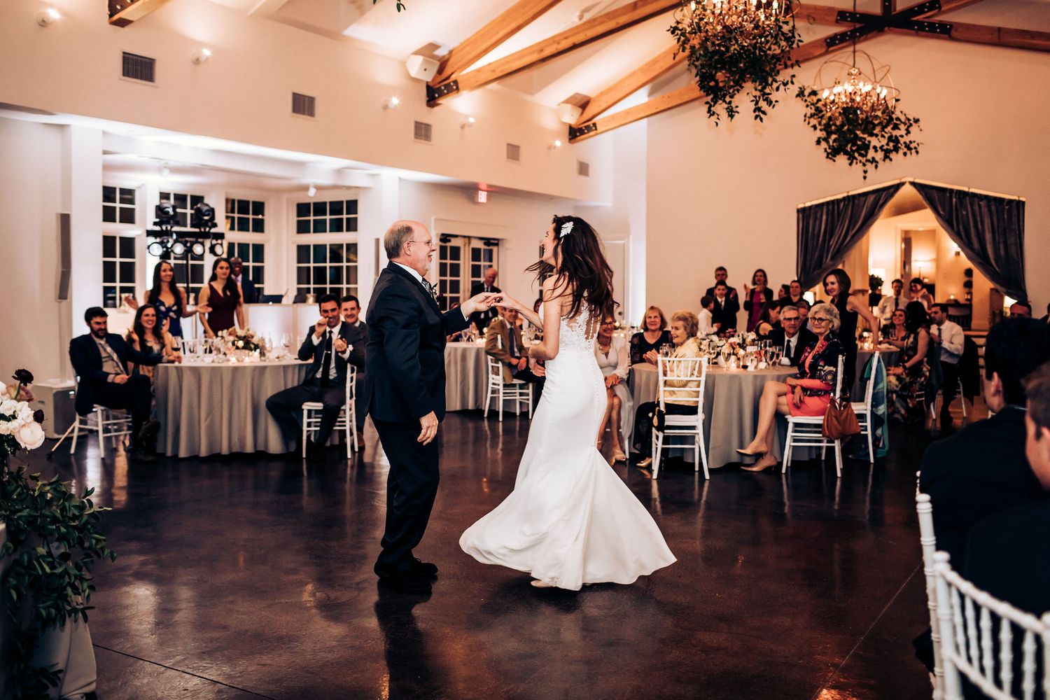 A dance performance in a beautifully decorated reception hall with guests seated at round tables.