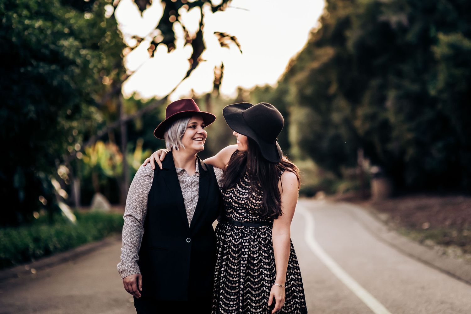 Two people share a tender moment on a garden path at sunset.