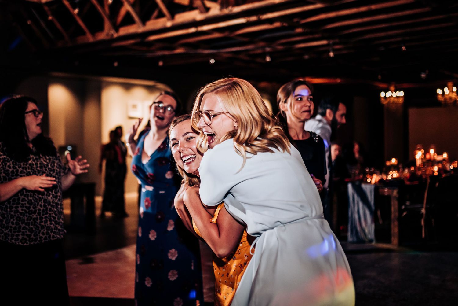 Guests dancing and celebrating at evening wedding reception with mood lighting.