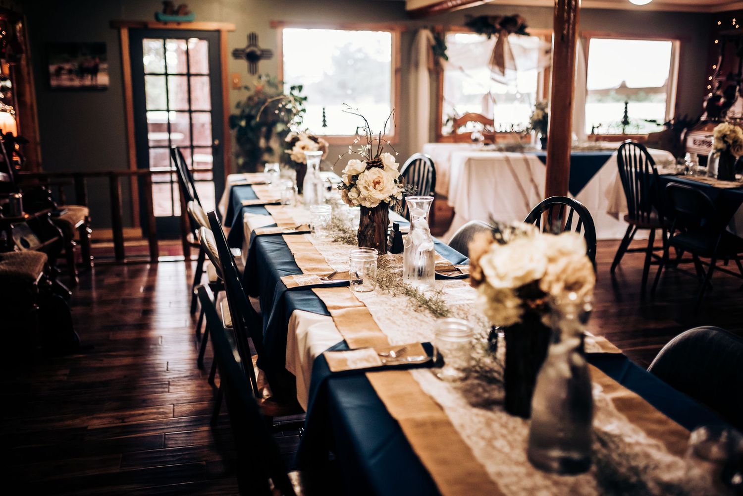 Elegant rustic wedding reception venue with long wooden tables and white table runners.