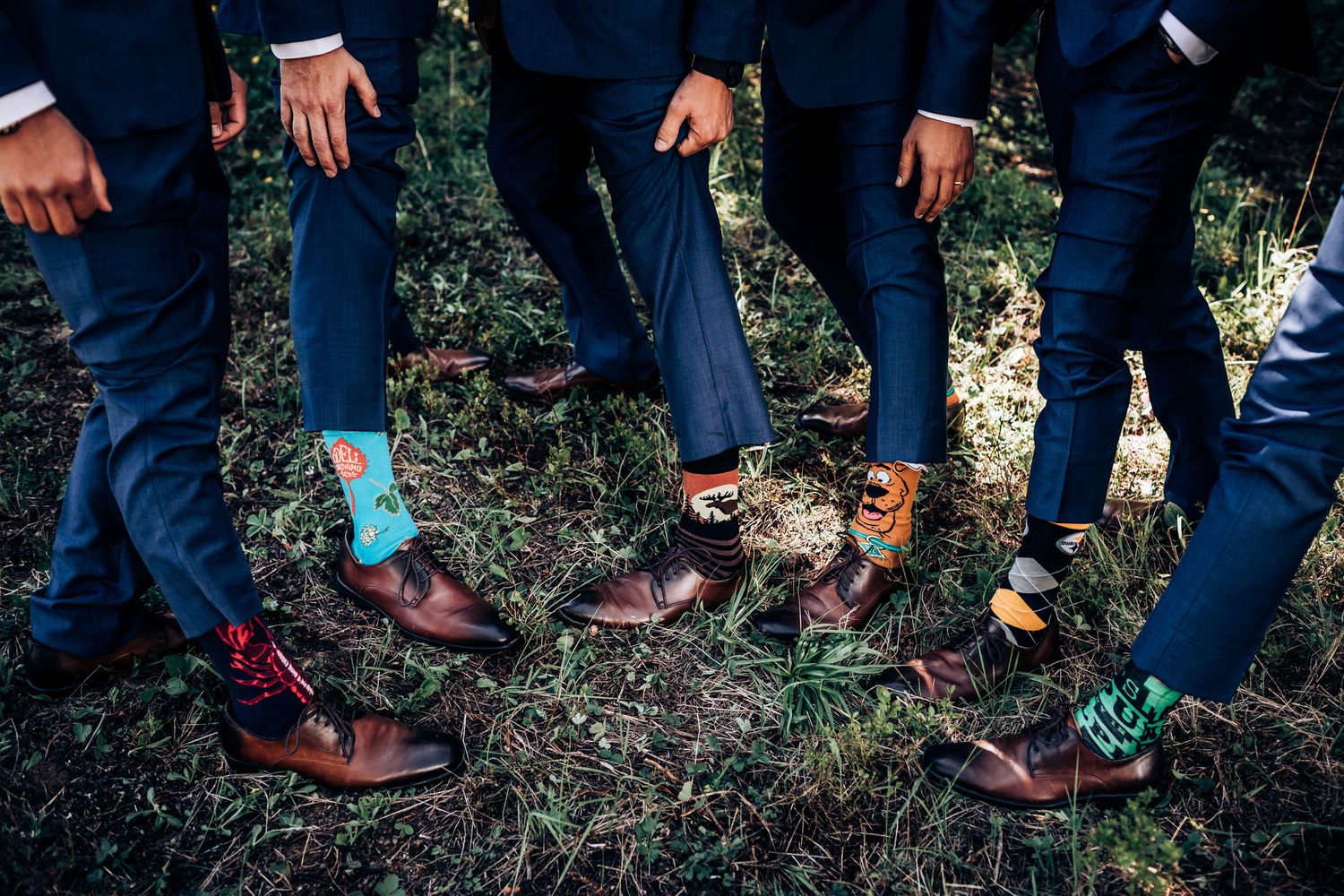 Detail shot of groomsmen's feet showing colorful socks and brown leather dress shoes.