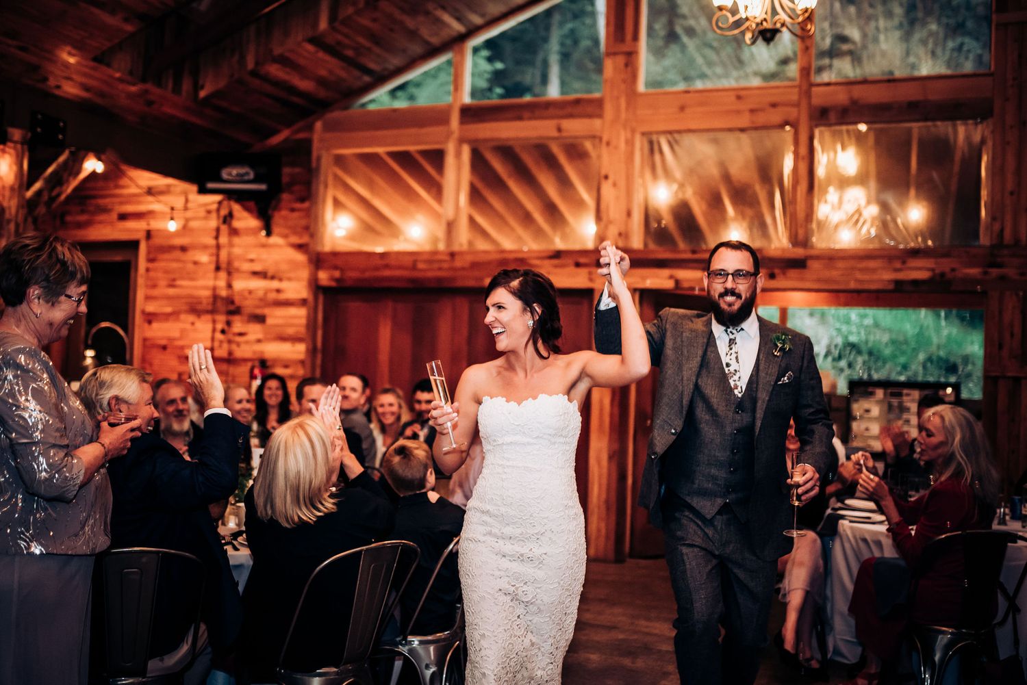 Wedding entrance celebration in rustic wooden barn venue with natural lighting.