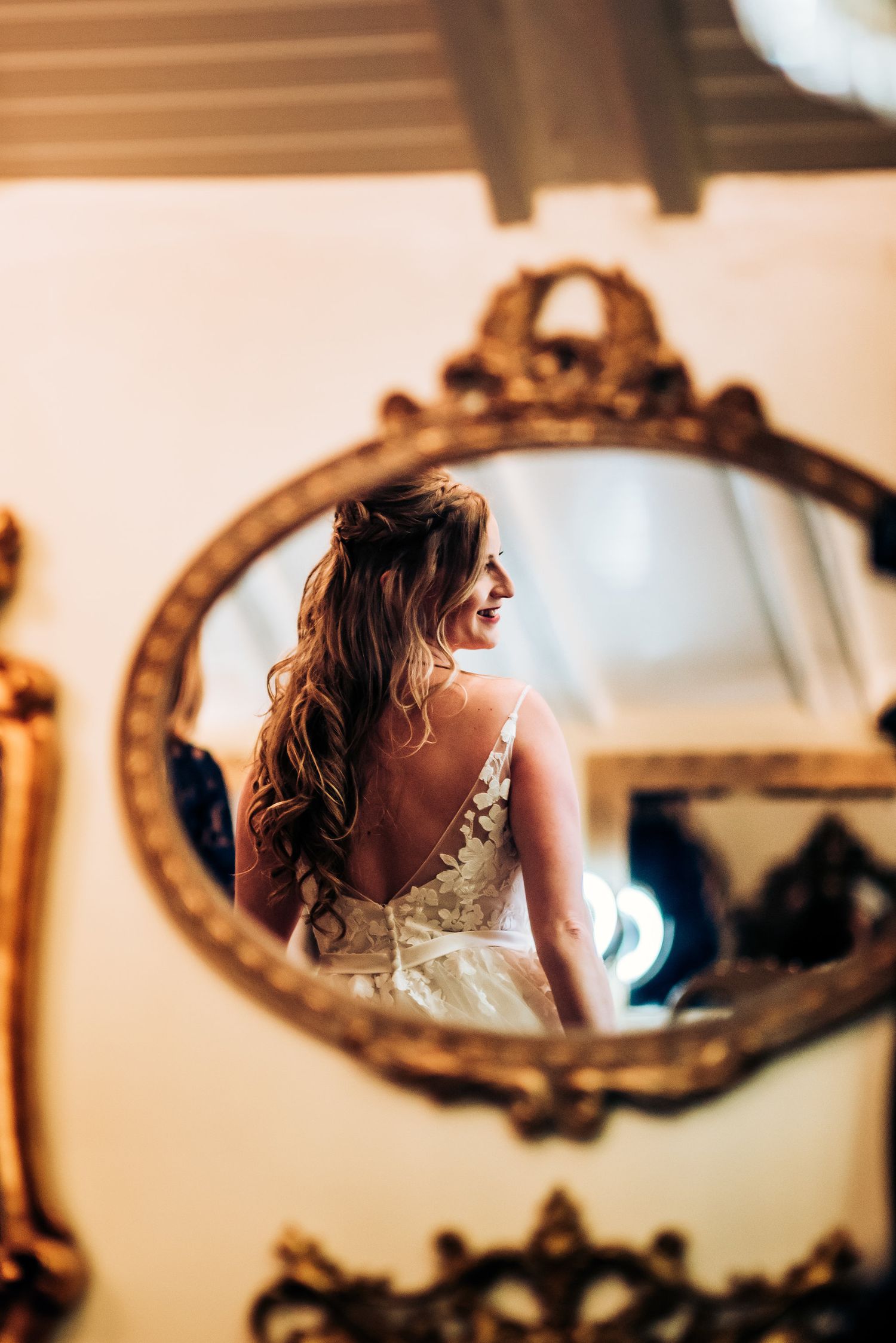Back view of wedding dress with lace details reflected in vintage gold mirror.