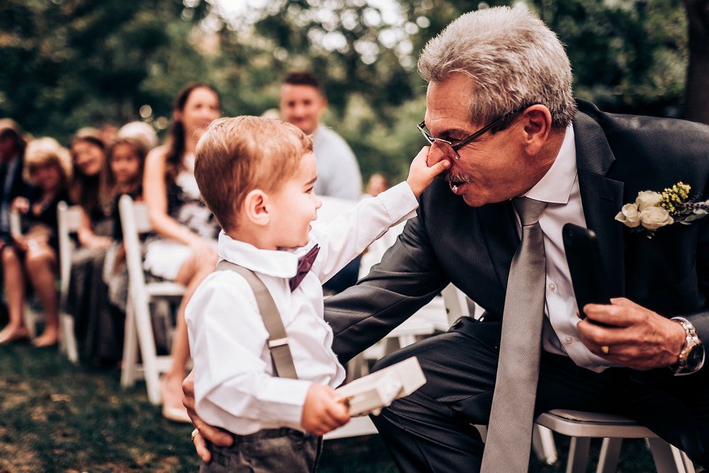 Tender moment between wedding guest and young attendant during outdoor ceremony.
