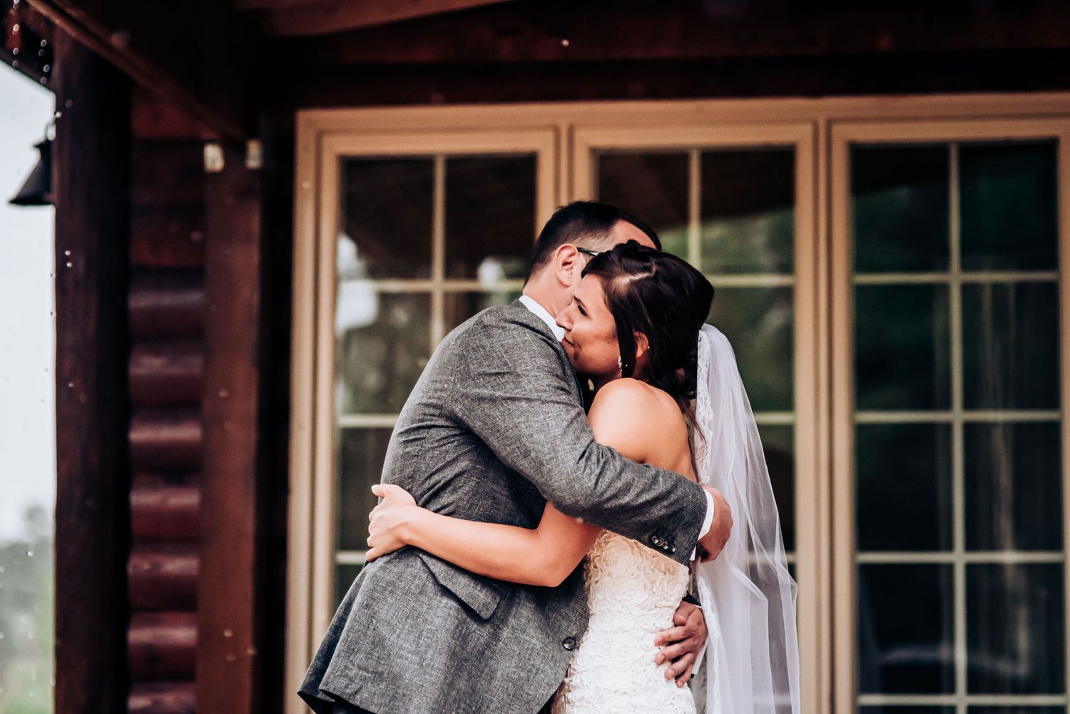 Intimate moment between newlyweds embracing on rustic cabin porch.