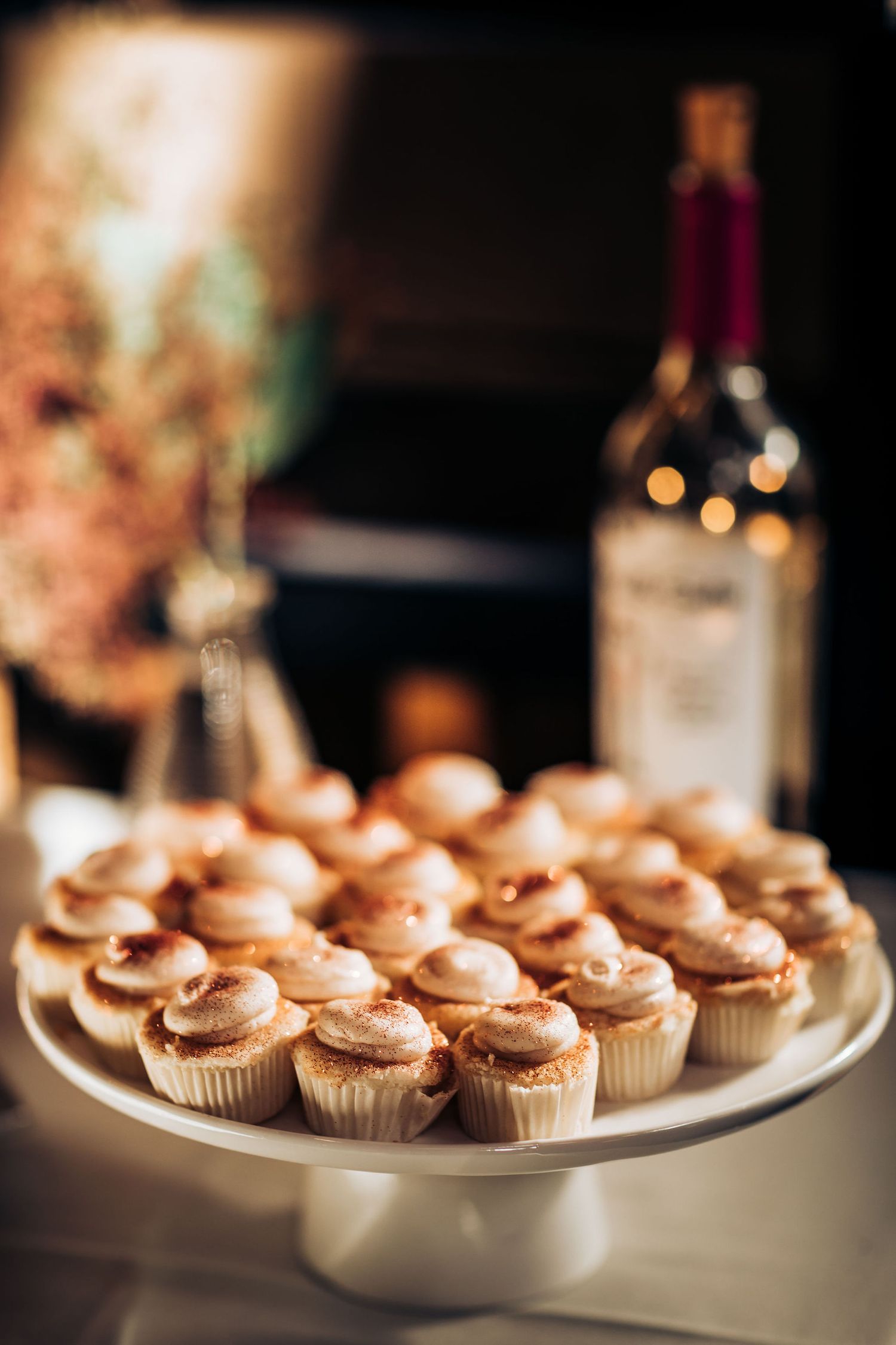 Display of vanilla cupcakes with caramel frosting on white cake stand.