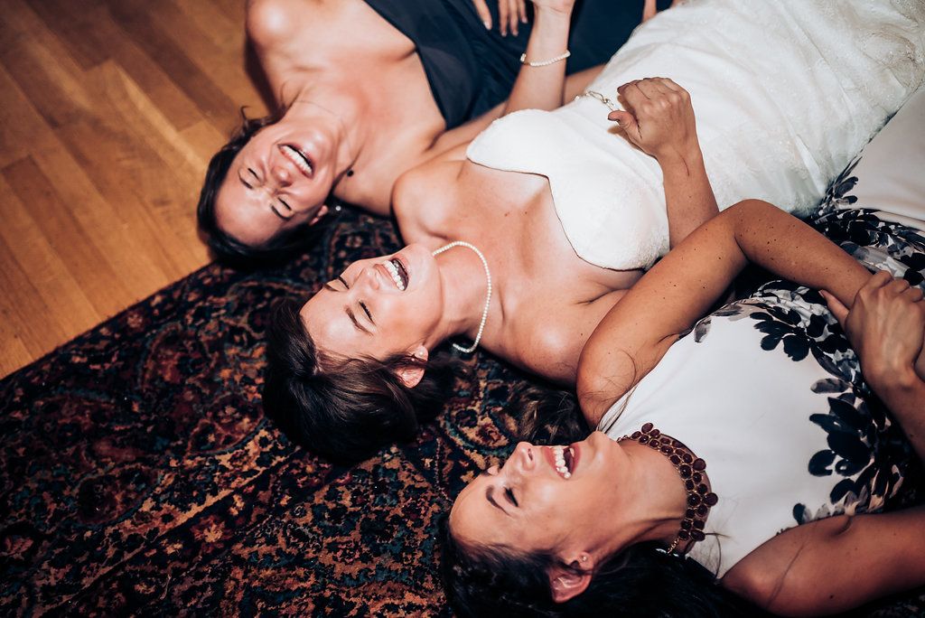 Three people lying on a decorative rug laughing together during a celebration.