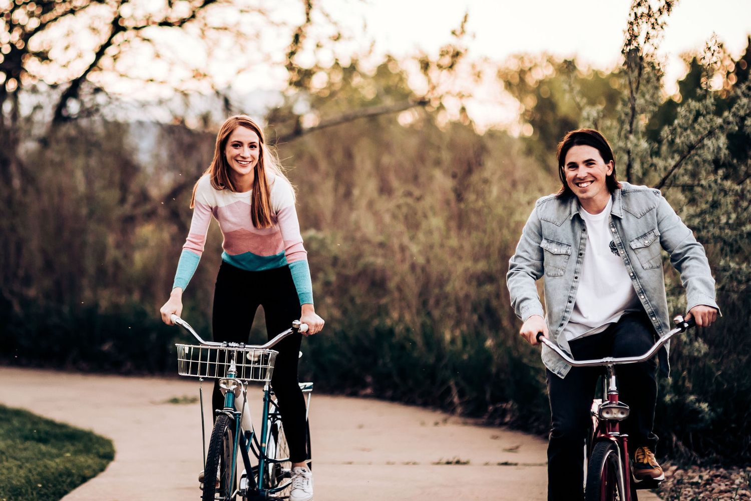Two people riding bicycles together on a scenic pathway at dusk.