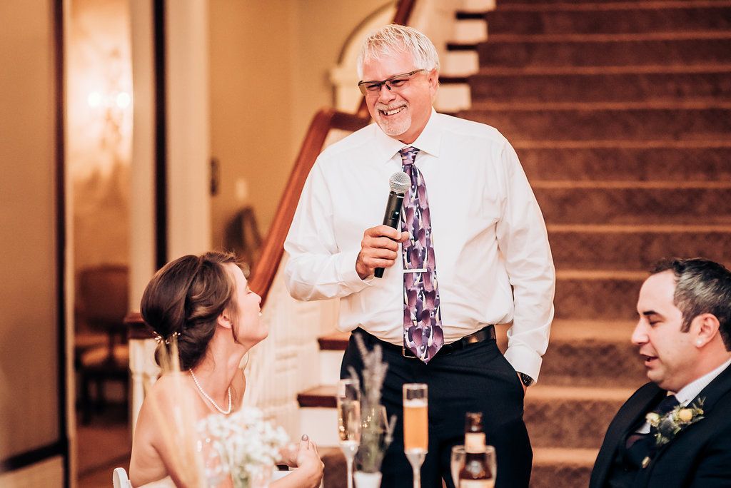 Candid moment of laughter shared during wedding reception speeches.