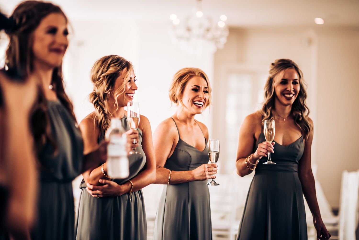 Group wearing matching formal dresses sharing laughs with champagne glasses.