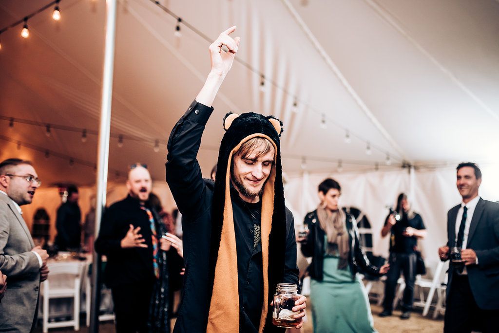 Guest dances joyfully at reception with string lights overhead.