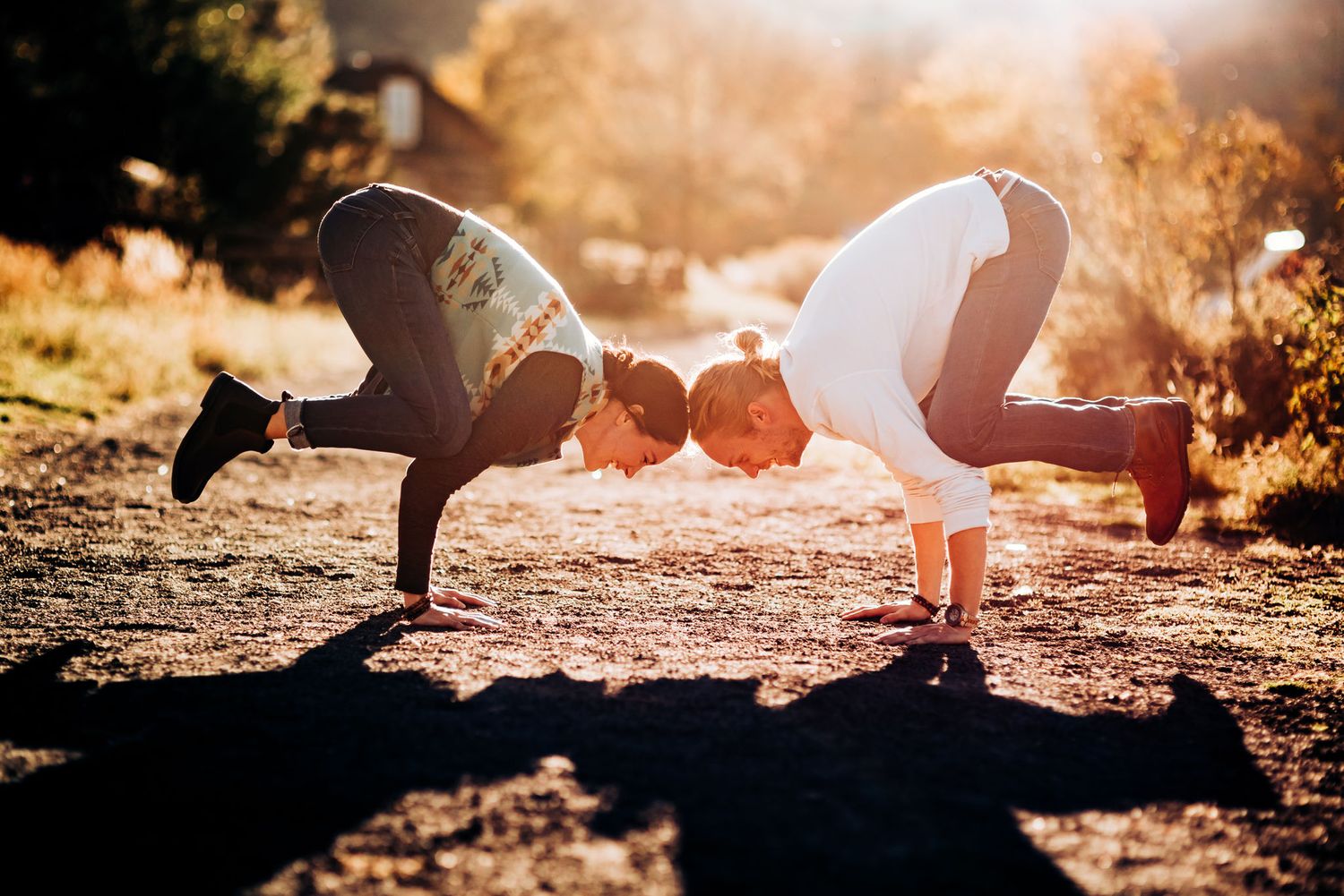 Two people leaning forward to touch foreheads in playful pose during golden hour.